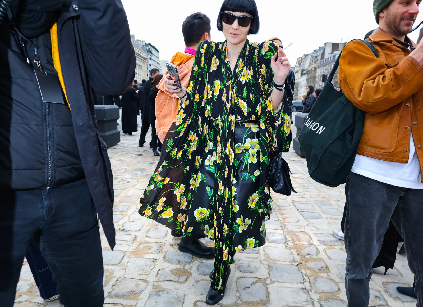 woman with sunglasses wearing a black dress with green and yellow flowers