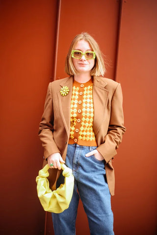 woman with camel blazer, orange cardigan and bright yellow handbag