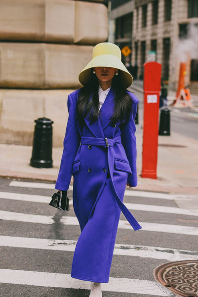 woman with purple coat and big, yellow hat