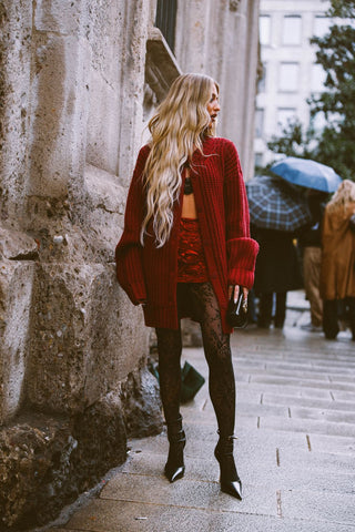 woman with long wavy blond hair, burgundy long cardigan and burgundy mini skirt