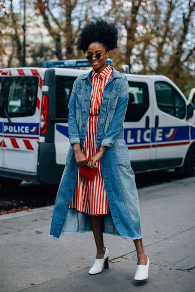 woman wearing a striped red shirtdress and denim overcoat