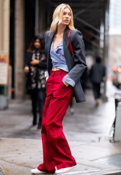 woman wearing a grey blazer, a striped shirt and wide, red pants