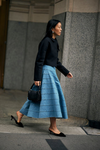 woman with black short blazer, blue full skirt and black kitten heels
