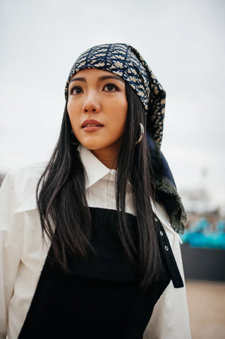 woman with scarf on hair, white shirt and silver earhoops