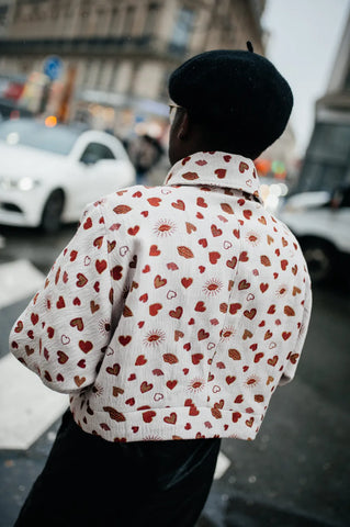 woman with a black beret hat and a heart-printed bomber jacket