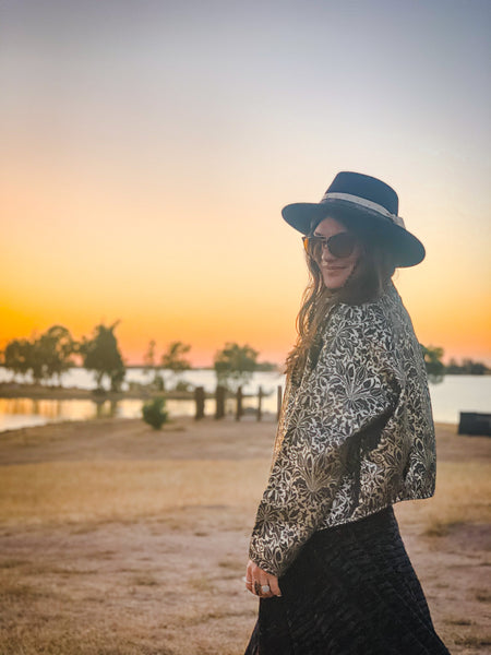 woman posing with black wide brim hat in front of reservoir during the golden hour 