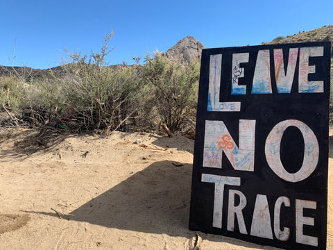 a leave no trace wood painted sign in the middle of the desert