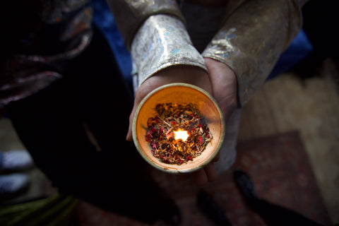 woman's hands holding a ceramic bowl filled with loose incense