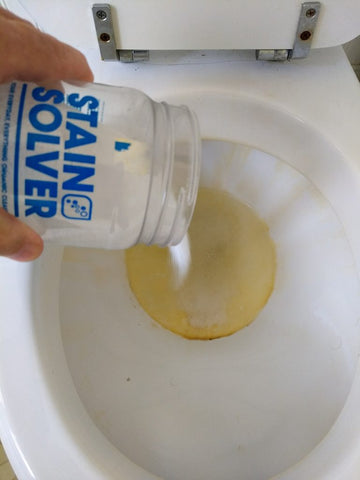 stain solver being poured into a stained toilet bowl