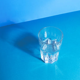 verre d'eau posé sur un fond bleu