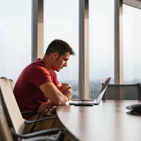 man sitting at a desk looking at his computer exhaustedly