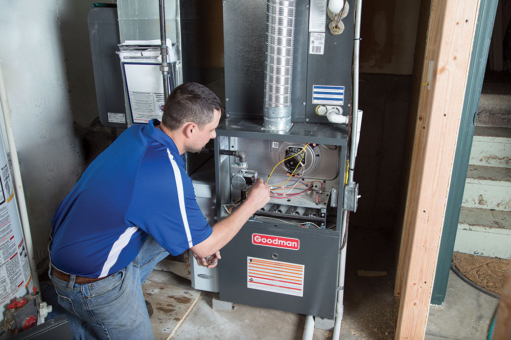 man installing Goodman gas furnace in basement of home
