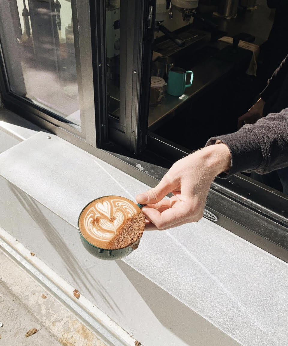 Latte being handed to a customer from a drive through window.