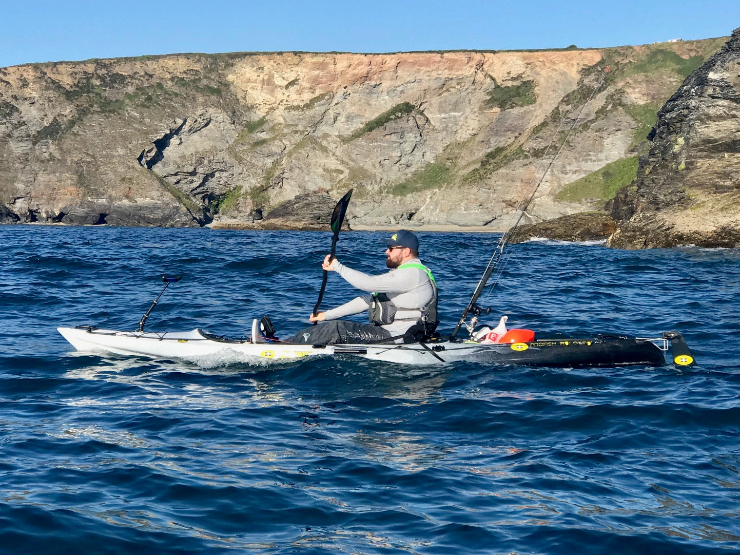 Paddling a fishing kayak whilst wearing a buoyancy aid on the sea