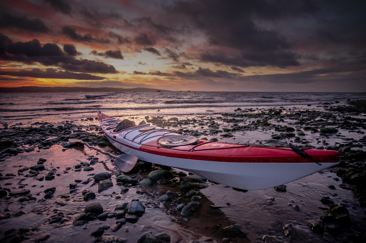 The Norse Bylgja Sea Kayak on a beach with the sun setting