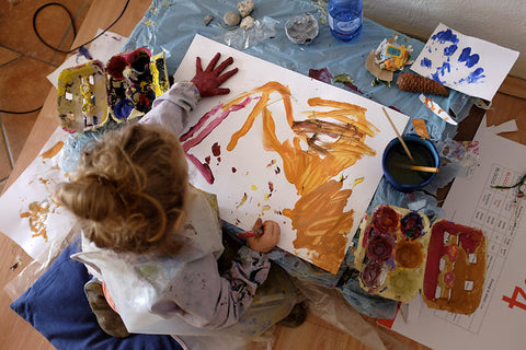 Bird's eye view of a young artist creating a painting using their hands