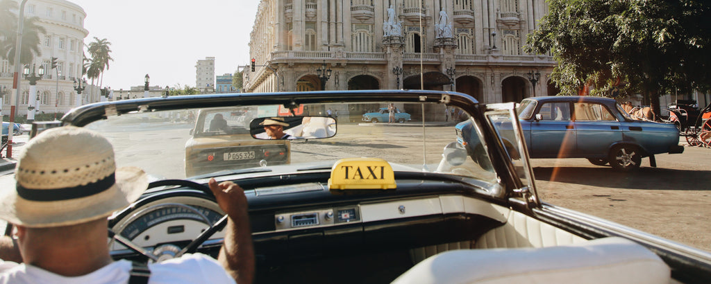 Blick aus einem Taxi-Cabrio in einer sonnigen Stadt mit Palmen