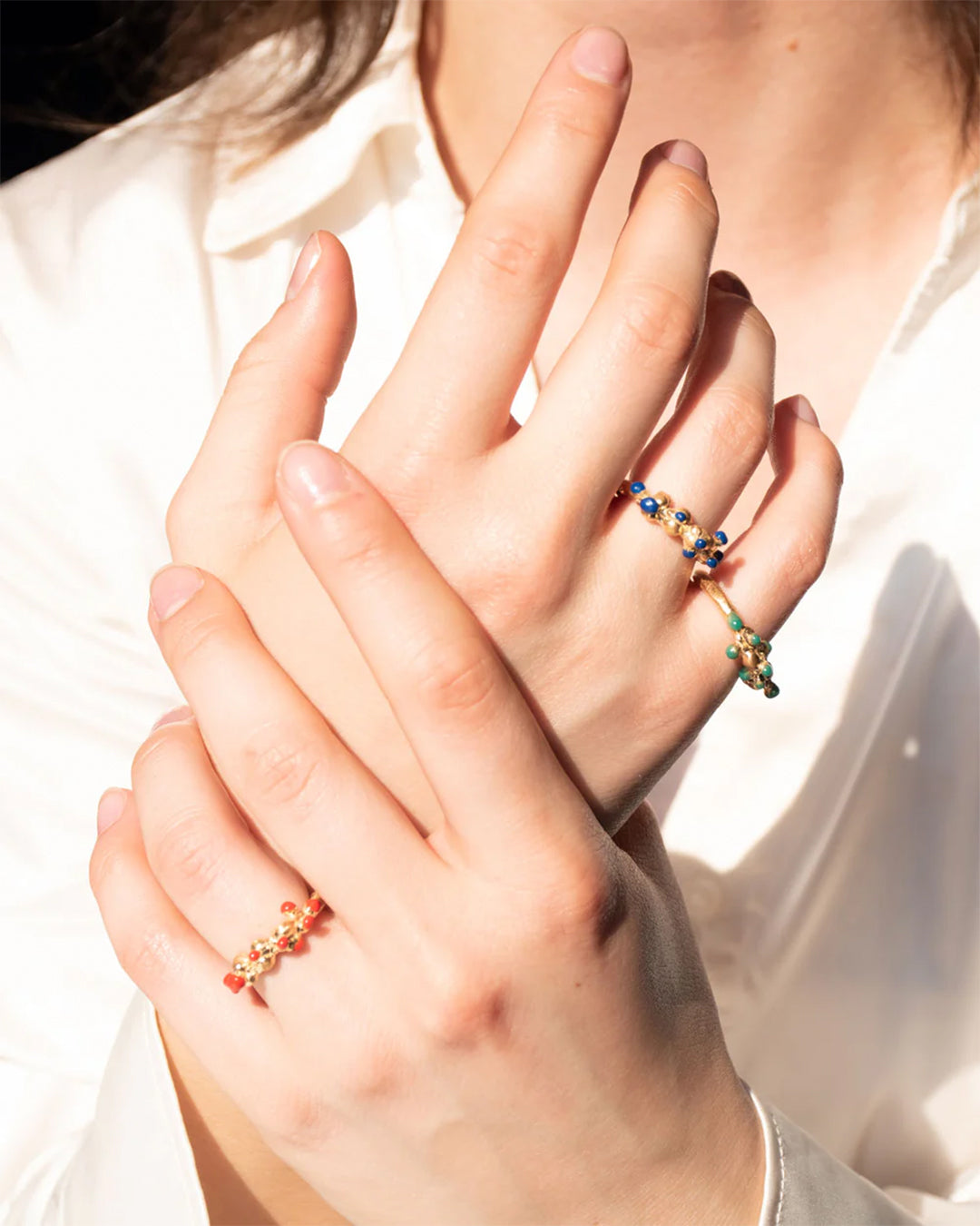 Close-up of a creative hand adorned with vibrant, handcrafted memory rings, showcasing artisan jewelry