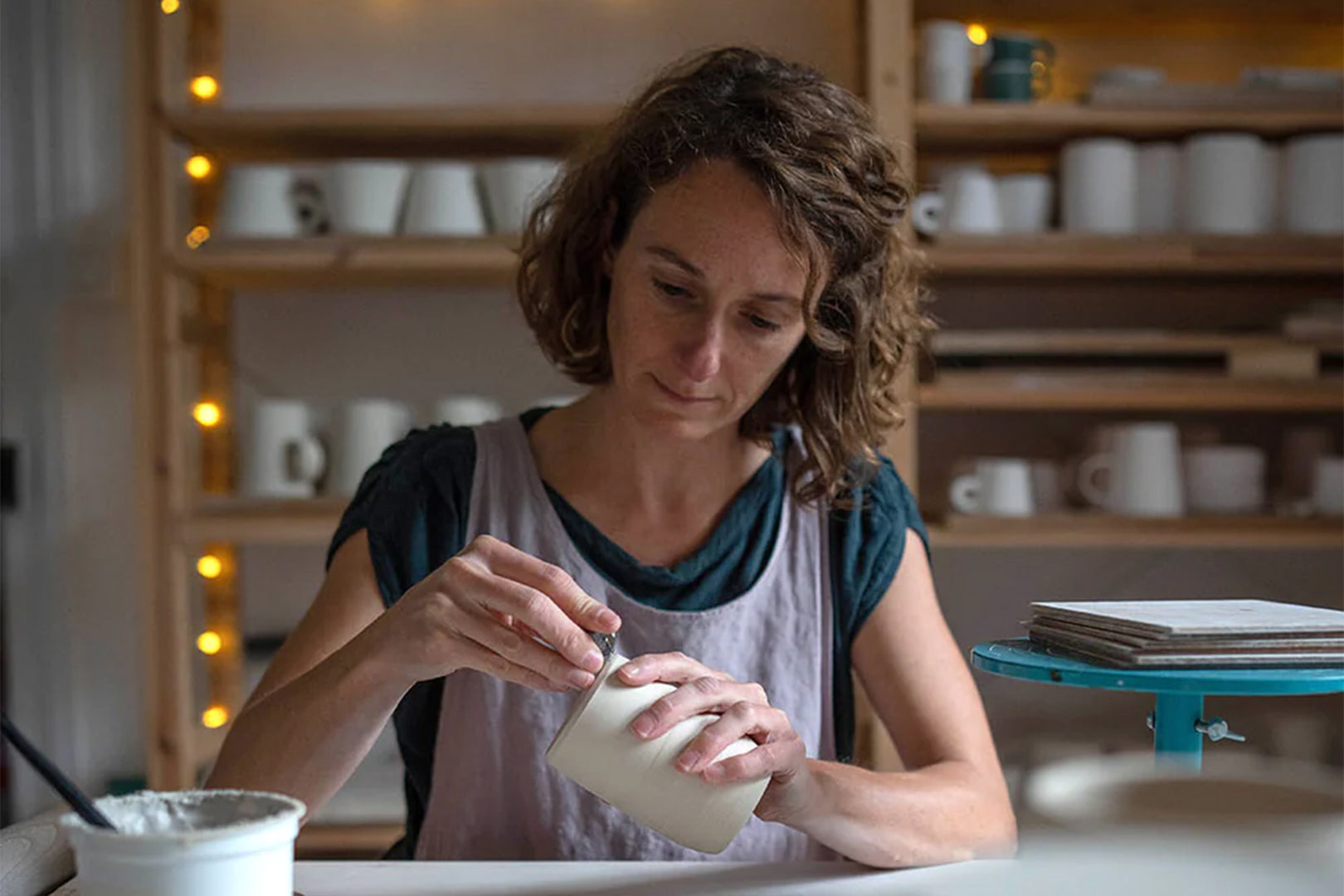 A potter Marie’s hands delicately finish the surface of a ceramic piece, showcasing the detail-oriented aspect in the craft.