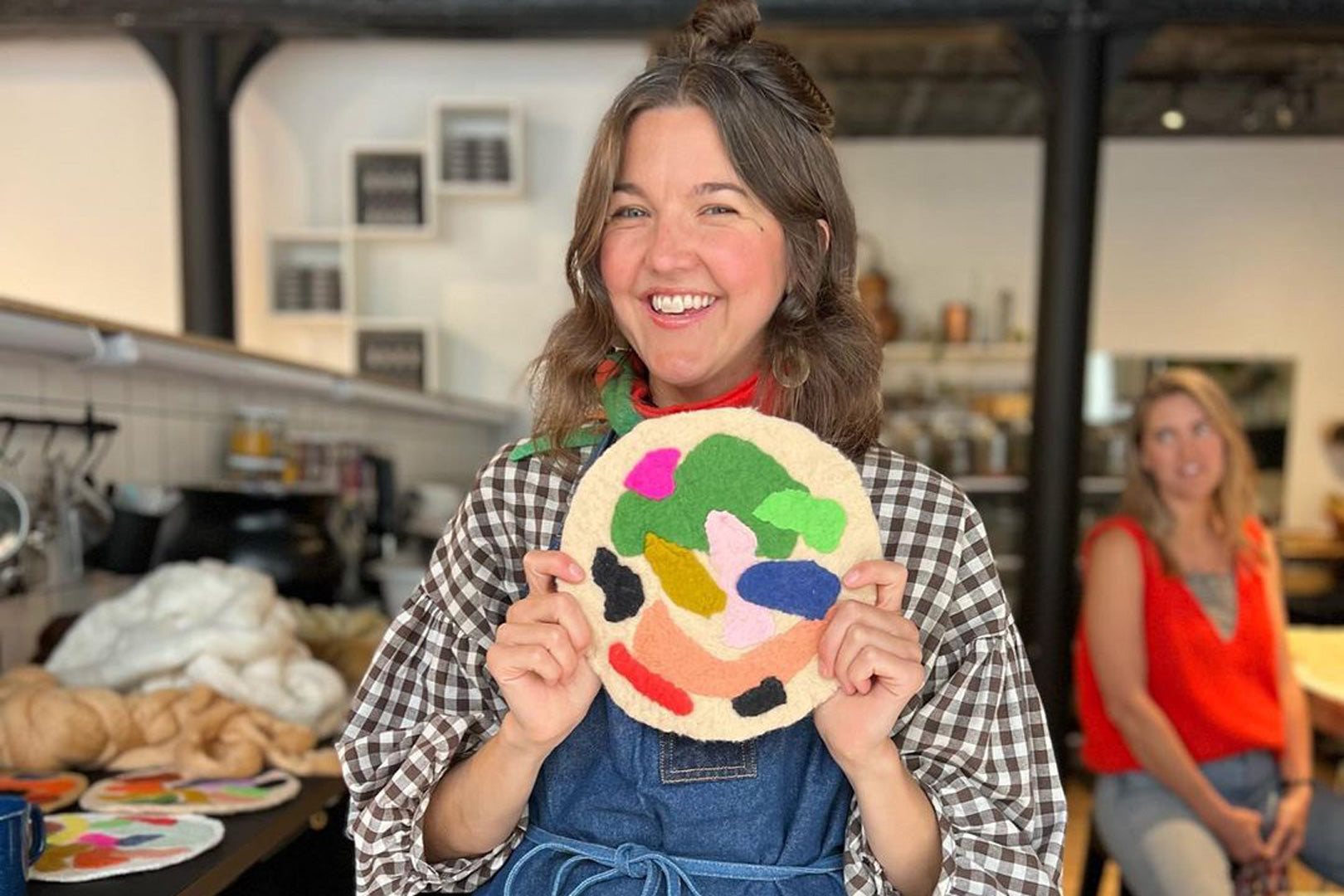 Proud artist showcasing a handmade felt art piece with multicolored patterns, in a creative studio setting