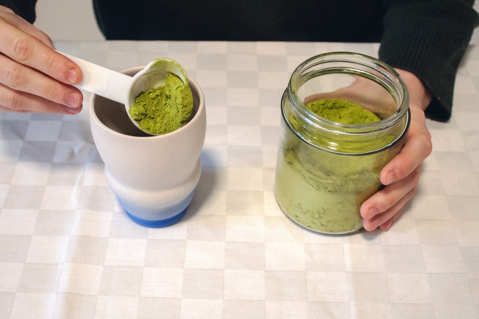 Ingredients for a homemade matcha latte arranged on a table, featuring matcha powder and honey.