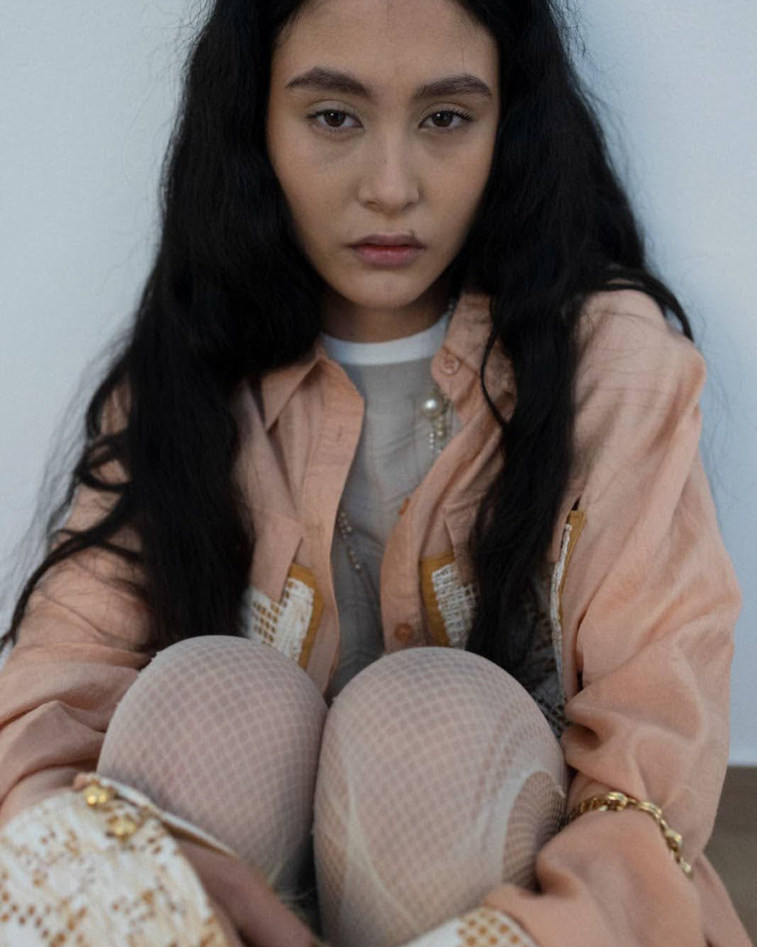 Portrait of a young woman in a relaxed pose, wearing a textured, pastel outfit, promoting eco-conscious choices.