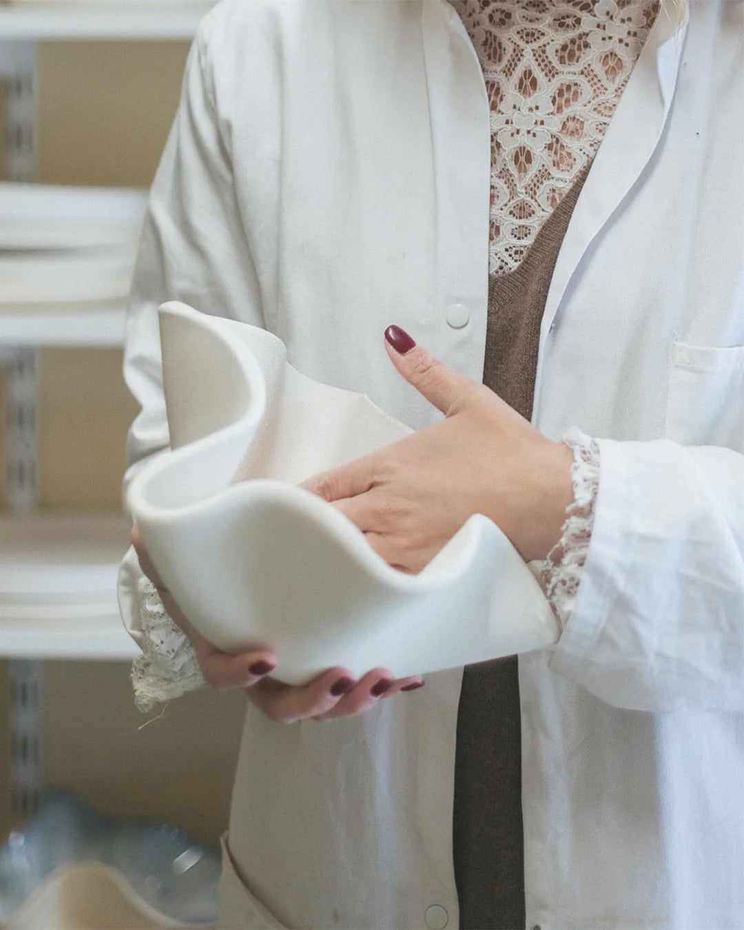 Close-up of an artisan holding a white ceramic design.