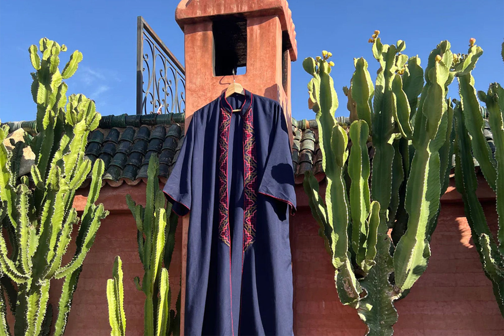 A vibrant fashion garment displayed outdoors, surrounded by cacti, symbolizing the integration of nature in eco-friendly fashion.