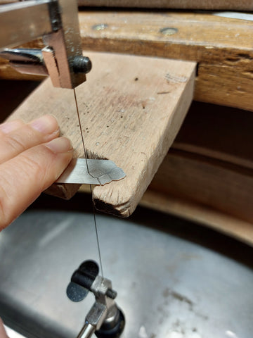 Découpe à la main, d'une plaque en argent qui sera la base de mon bijou.