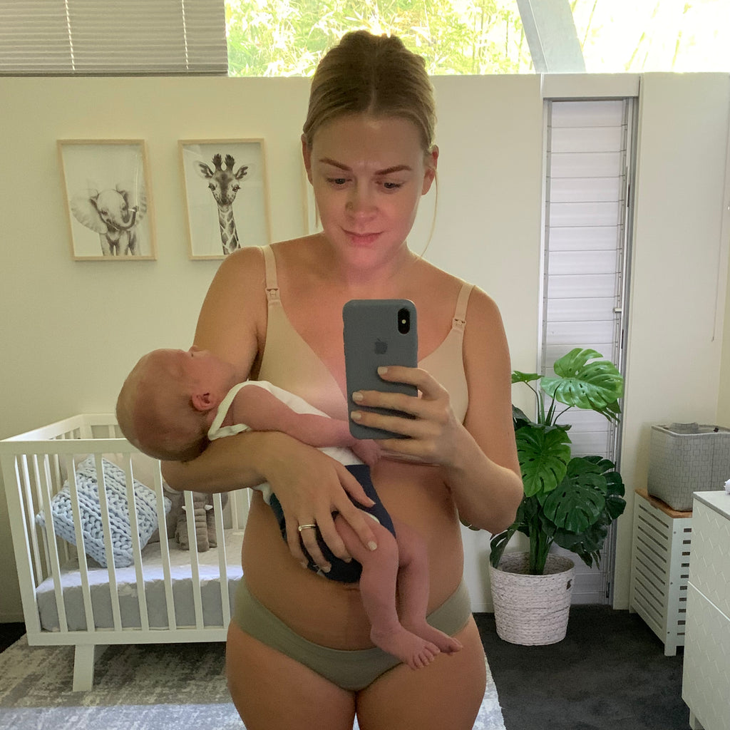 Shannon from Mothers Mylk stands with her newborn Hunter looking into the mirror.