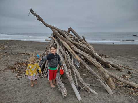 Kids playing at a Driftwood teepee on Moonstone Beach in Cambria