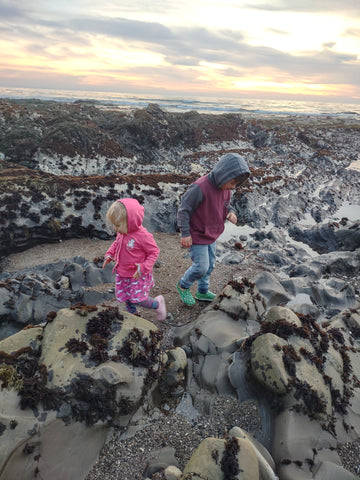 Two kids searching tidepools for anemones in Pismo Beach during a negative low tide