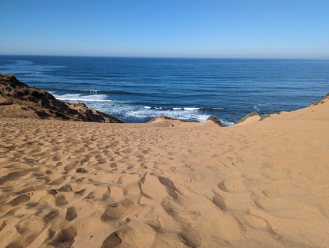 Kids play in a hole they dug as the waves crash while sitting on a large sand dune in montana de oro, san luis obispo county, california's central coast.