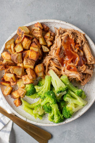 crockpot pulled pork on a plate with veggies and potatoes