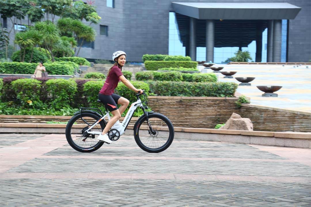 En flicka tycker om att cruisa på stadsvägar på shengmilo mx06 genomgående elcykel.