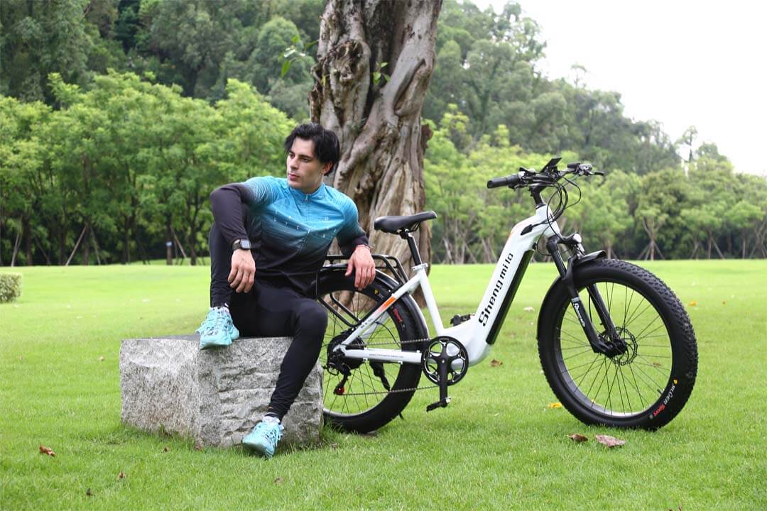 Άνδρας που στηρίζεται στο ηλεκτρικό ποδήλατο Shengmilo MX06 stride