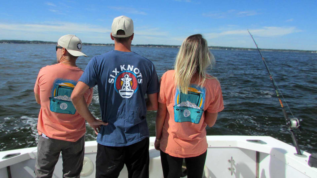 Two guys and a girl with their backs turned looking at the ocean