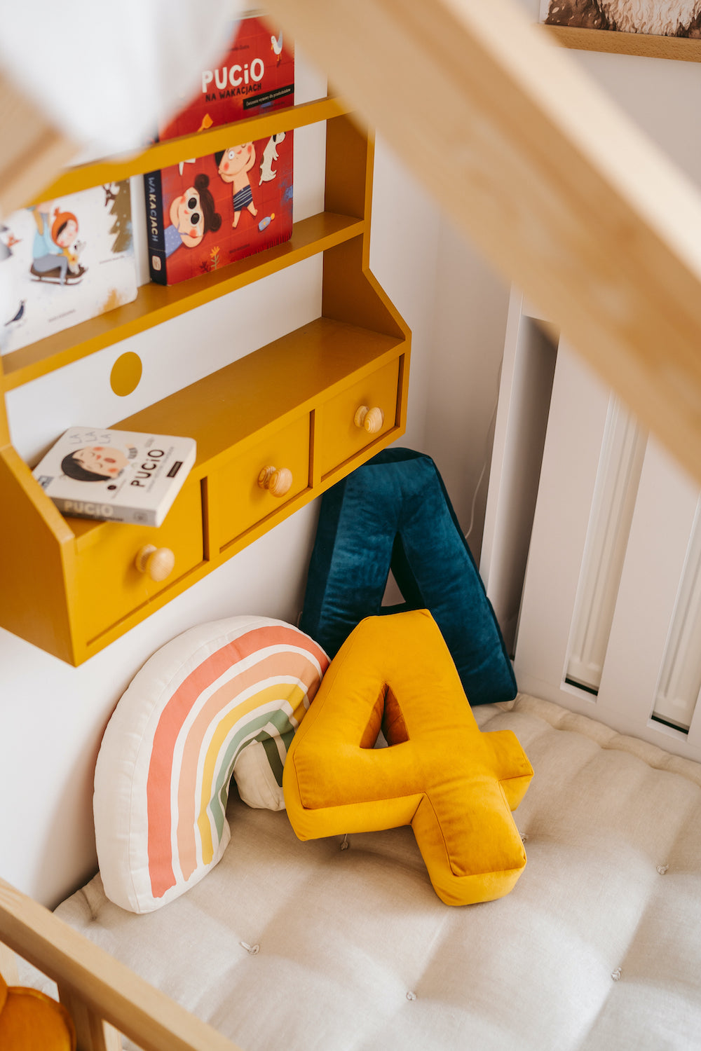 coussin numéro 4 en velours jaune sur un lit d'enfant