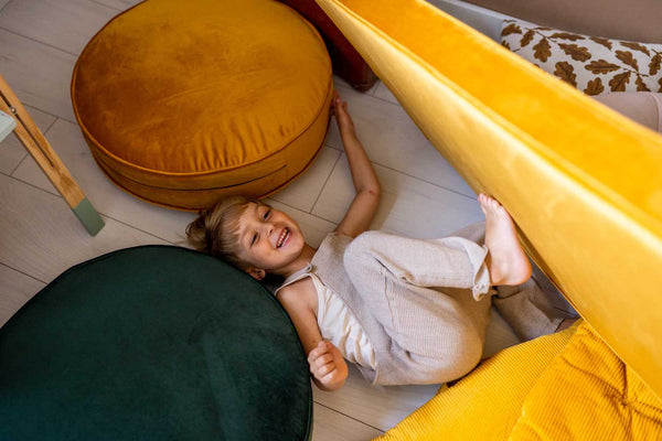 cute boy on playing on large velvet pouf in green and yellow