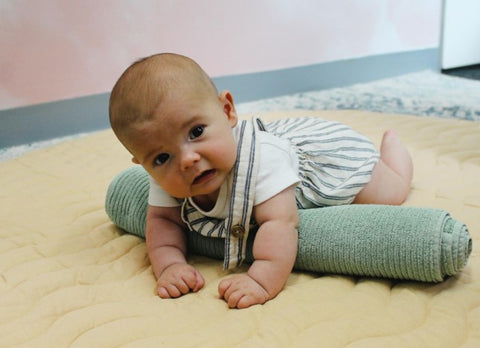 Baby dong tummy time on a rolled up towel