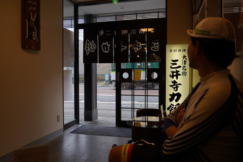 三井寺力餅の店内から路面電車を眺める人を撮影