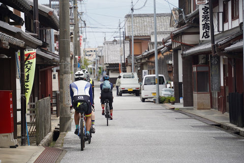 八幡堀の街中を自転車で走る3人を背後から撮影