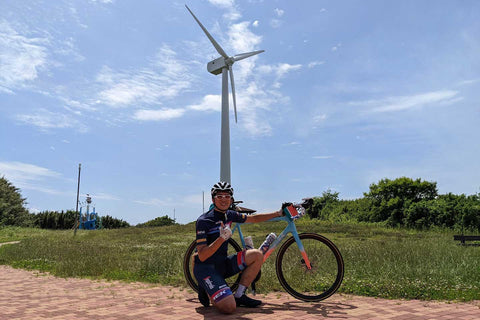 宮川公園の風車と写真を撮っているスタッフ中村とエモンダALR