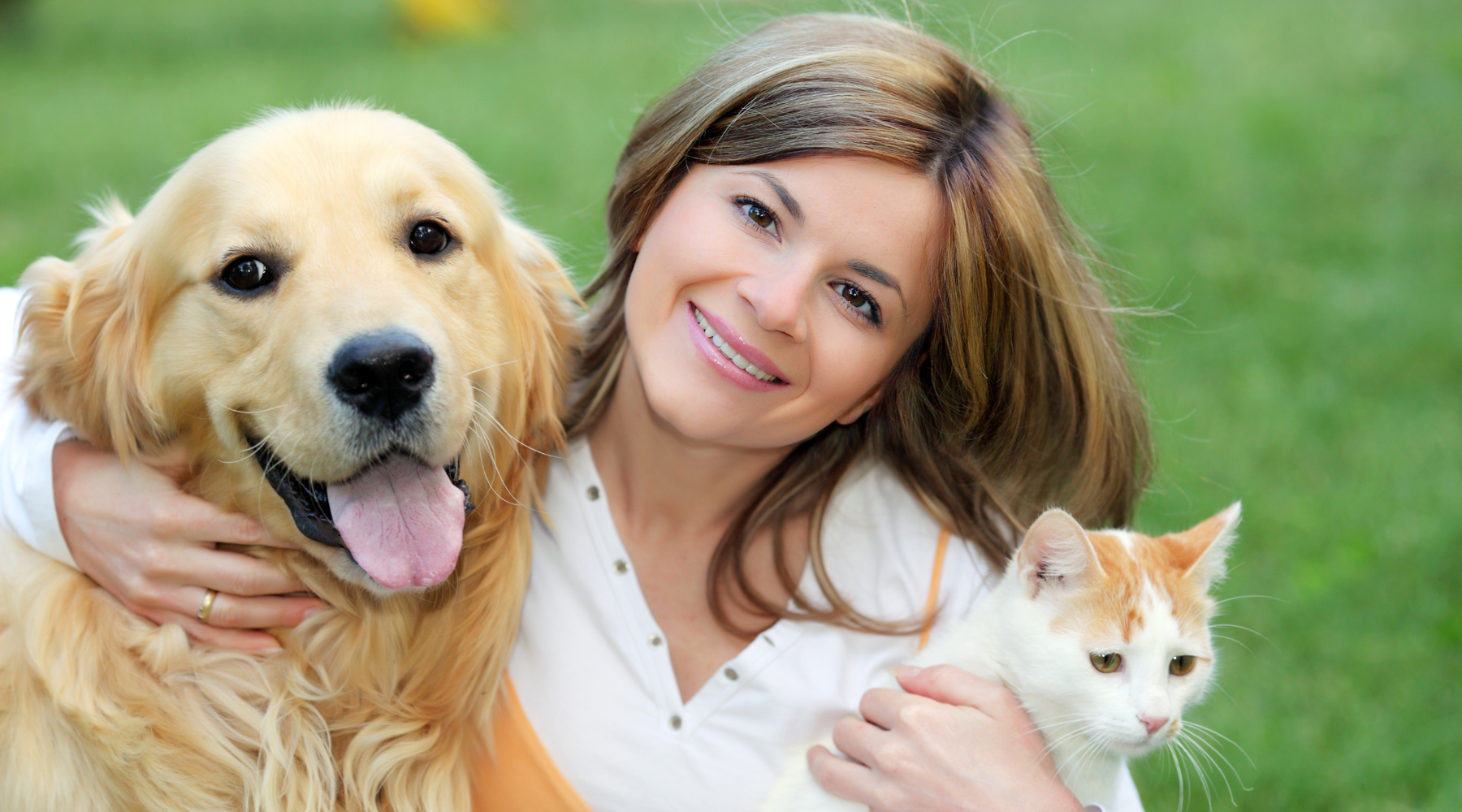 Lady smiling while holding her cat and dog