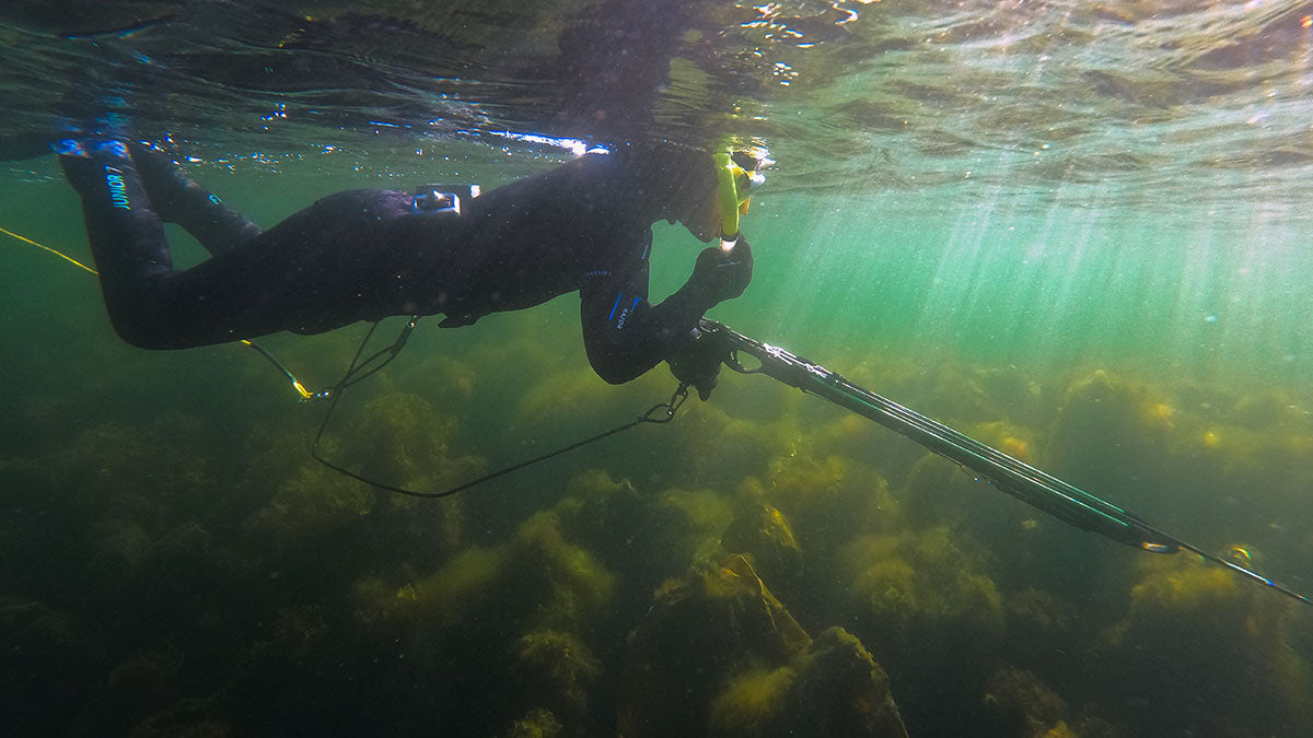 Joven apneista nadando en la superficie del agua con arpón