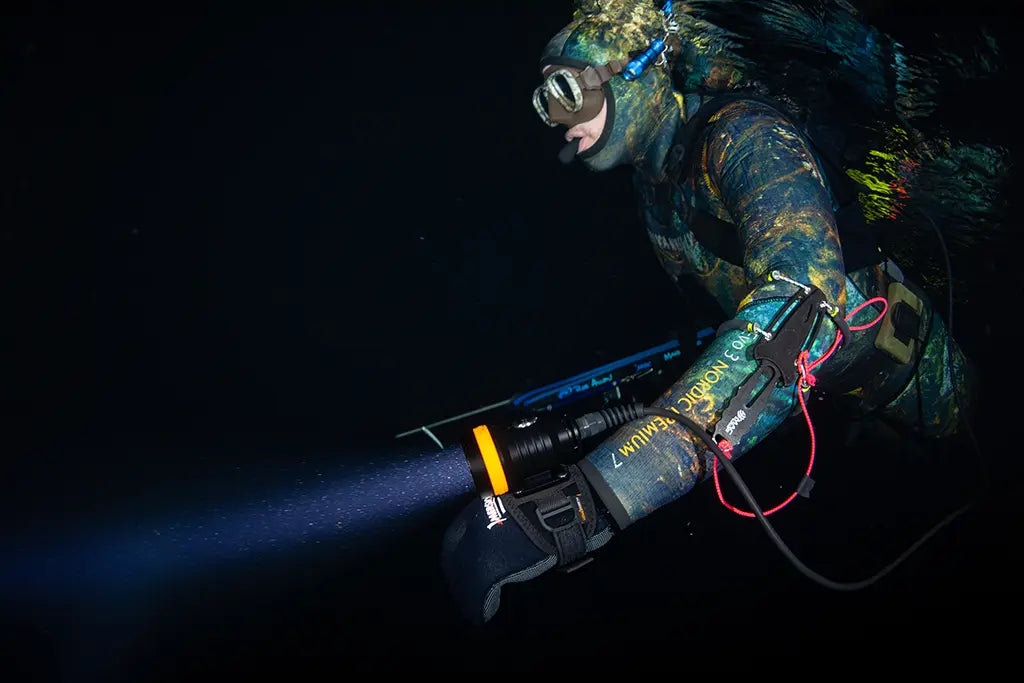 Freediver as a night diver with a diving light in Norway
