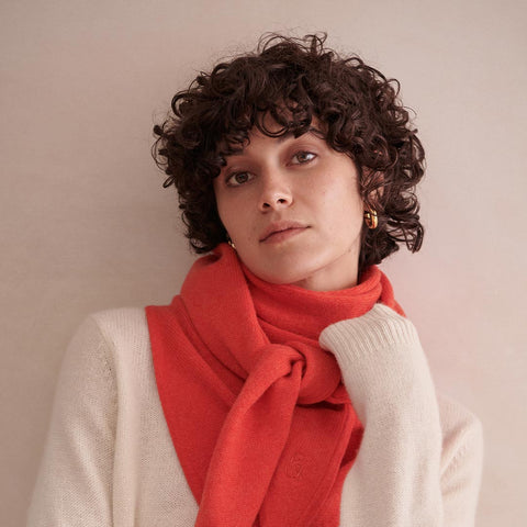 A picture of a model wearing a buttermilk cashmere jumper and classic red cashmere wool bandana