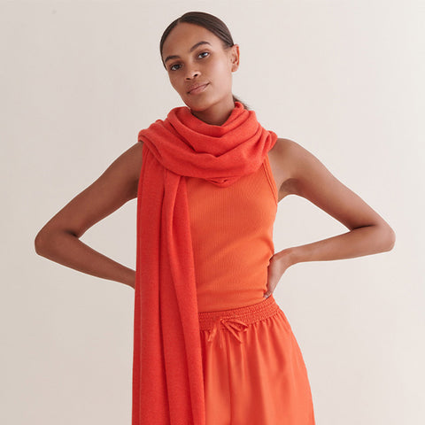 a model wearing an orange cashmere wrap around them like a scarf