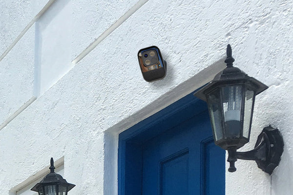 Toucan Wireless Security Camera PRO installed on top of blue front door of a house with white walls