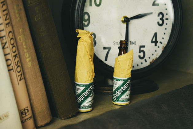 Two Underberg bitter bottles on a shelf with some books and clock